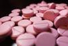 Pink nitroglycerine tablets scattered on a black background