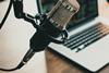 Close-up image of a microphone in front of a blurred-out aptop