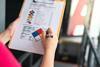 Someone fills in a hazardous chemical safety checklist on a clipboard
