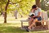 Father sitting on a bench with child reading a book