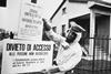 A black and white image of a policeman in Seveso, Italy pinning up warning signs written in Italian warning of chemical contamination of the area