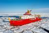 The RRS Sir David Attenborough with its bright red hull sailing through broken ice