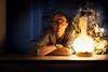 Moody and atmospheric portrait of Chemistry World columnist Andrea Sella, leaning on a worktop, illuminated by a flask.