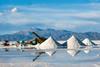 A working lithium mine with piles of salt and a view of the Andes mountain range behind