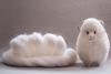 Roll of white wool next to a handmade woollen sheep, set on a neutral background