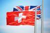 Swiss and UK flag fluttering in the wind side by side