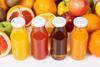 A photo of various fruit and fruit juices in glass bottles
