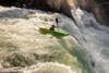 A kayaker in white water going over a waterfall