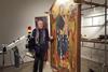 Rocco Mazzeo standing by a painting he is restoring