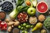 Looking down on a colourful assortment of fruit, nuts and vegetables on a grey marble worktop