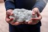 Pair of hands holding a white aggregate rock of crystals