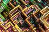 Bismuth crystals close up, geometric swirls of green yellow and purple