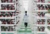 A female researcher in a lab coat walk through an agricultural research facility where red plants are grow in towering hydroponic sytems