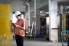 An inspector wearing PPE checking a manufacturing environrment