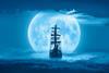 Sailing old ship in a storm sea with full moon stormy clouds in the background
