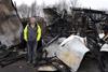 A man stands in front of a building that's burned down