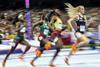 Female track runners competing in a race at a full stadium