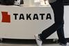 Visitor walking past Takata sign in vehicle showroom - Index