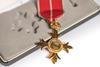A gold cross shaped medal with a red ribbon
