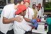 A scientist helps two visually impaired high school students perform a chemistry experiment with a bottle of fizzy drink and a balloon. The students are smiling as they feel the changes to the objects.