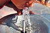 A woman taking a drink from an outdoor water fountain