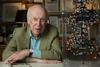 A photograph of James Watson sitting next to a molecular model of DNA's double helix
