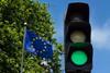 A green traffic light next to an EU flag