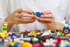 Close up of hands playing with colorful plastic bricks at a table