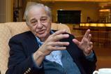 Rudolph Marcus sitting in an armchair gesturing with his hands as he speaks