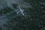 A military plane spraying liquid over a forested area