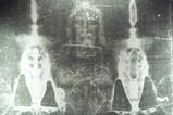 An enhanced black and white image of the Turin Shroud featuring a faint image of a bearded man's face some a damaged cloth
