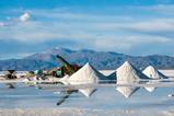 A working lithium mine with piles of salt and a view of the Andes mountain range behind