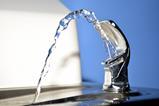 Close up of a public drinking fountain with a spout of water flowing out