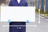 A man in a blue lab coat and latex gloves holding a white board 1 m by 0.5 m