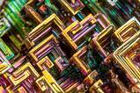 Bismuth crystals close up, geometric swirls of green yellow and purple