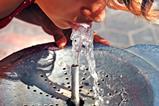 A woman taking a drink from an outdoor water fountain