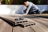 A man constructing a garden decking area using planks made of a composite materia