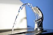 Close up of a public drinking fountain with a spout of water flowing out