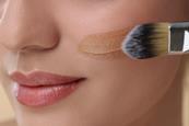 Close up of a woman's face applying foundation with a brush