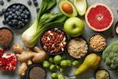 Looking down on a colourful assortment of fruit, nuts and vegetables on a grey marble worktop