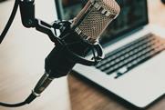 Close-up image of a microphone in front of a blurred-out aptop