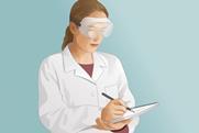 Science laboratory student wearing safety goggles and making notes