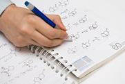 Hand writing organic chemistry structures in ballpoint pen on a notebook