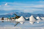 A working lithium mine with piles of salt and a view of the Andes mountain range behind