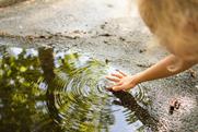 Child's hand touching water from a puddle