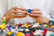 Close up of hands playing with colorful plastic bricks at a table