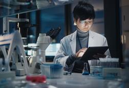 A scientist uses a tablet at a desk in a laboratory