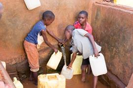 A group of Ugandan boys filling jerrycans with water in a local water well.