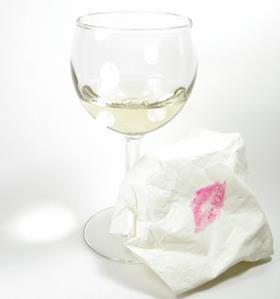 Lipstick marks on a tissue next to a wine glass