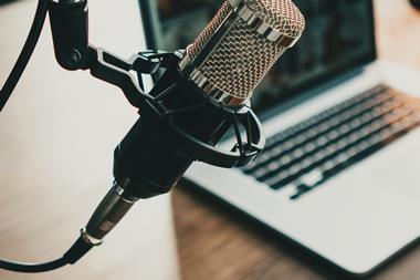 Close-up image of a microphone in front of a blurred-out aptop